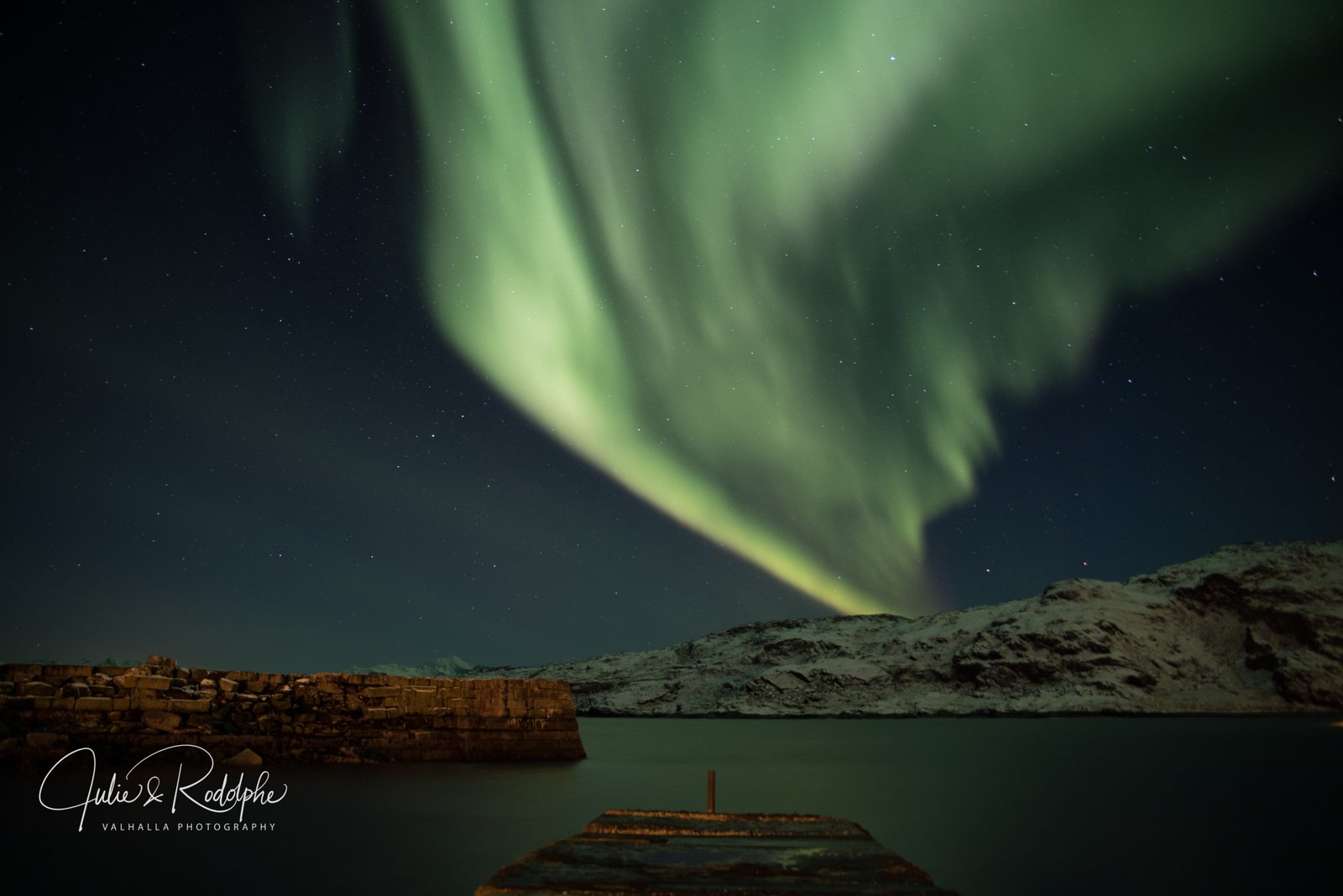 green northern light behind mountain on pontoon